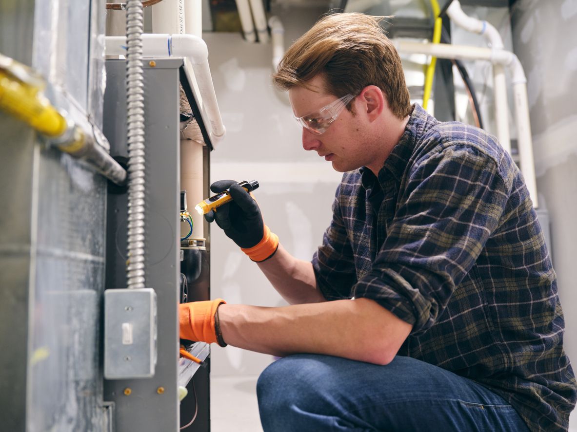 Elwood Heating Inc. technician inspecting a gas furnace in an Elwood, NY home